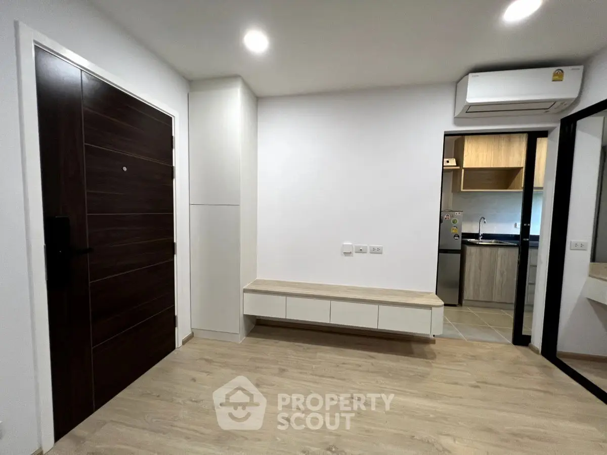 Modern apartment entrance with wooden flooring and sleek kitchen view