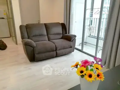 Cozy living room with plush sofa and balcony access, perfect for relaxation.