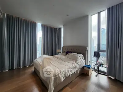 Luxurious bedroom with floor-to-ceiling windows and city view, featuring elegant curtains and modern decor.