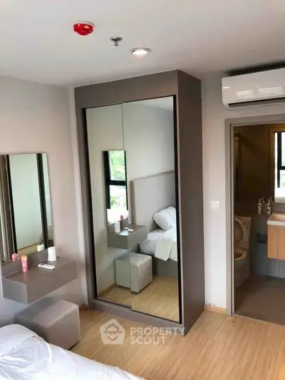 Modern bedroom with mirrored wardrobe and ensuite bathroom in stylish apartment.