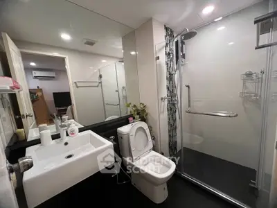 Modern bathroom with sleek design, featuring a glass shower enclosure and contemporary fixtures.