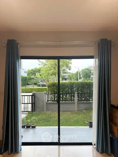 Spacious living room with large glass doors opening to a lush garden view.