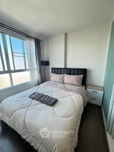 Cozy bedroom with large window and modern decor, perfect for relaxation and comfort.