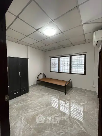 Spacious bedroom with modern tiled flooring and ample natural light.