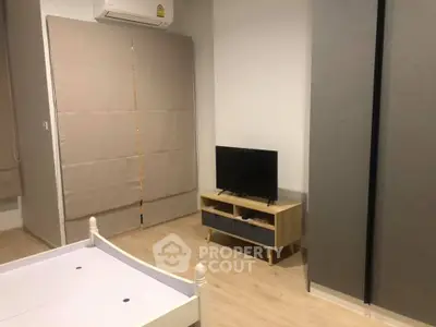 Modern bedroom with minimalist decor, featuring a TV stand and air conditioning.