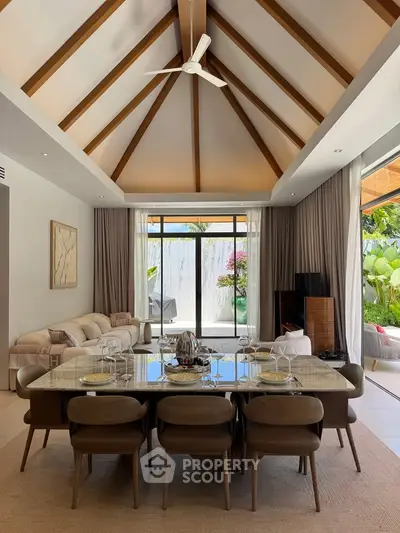 Luxurious open-plan living and dining area with vaulted ceiling and garden view.