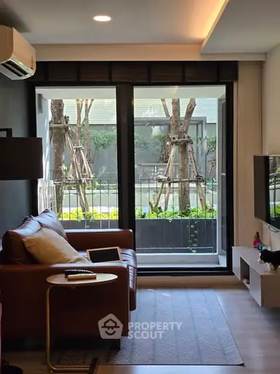 Modern living room with leather sofa and garden view through large windows.