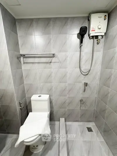 Modern bathroom with sleek tiles and water heater in a contemporary apartment.