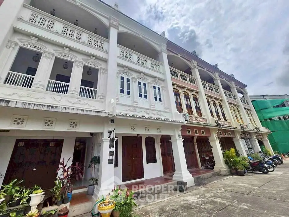 Charming colonial-style townhouses with ornate balconies and lush greenery in a vibrant neighborhood.