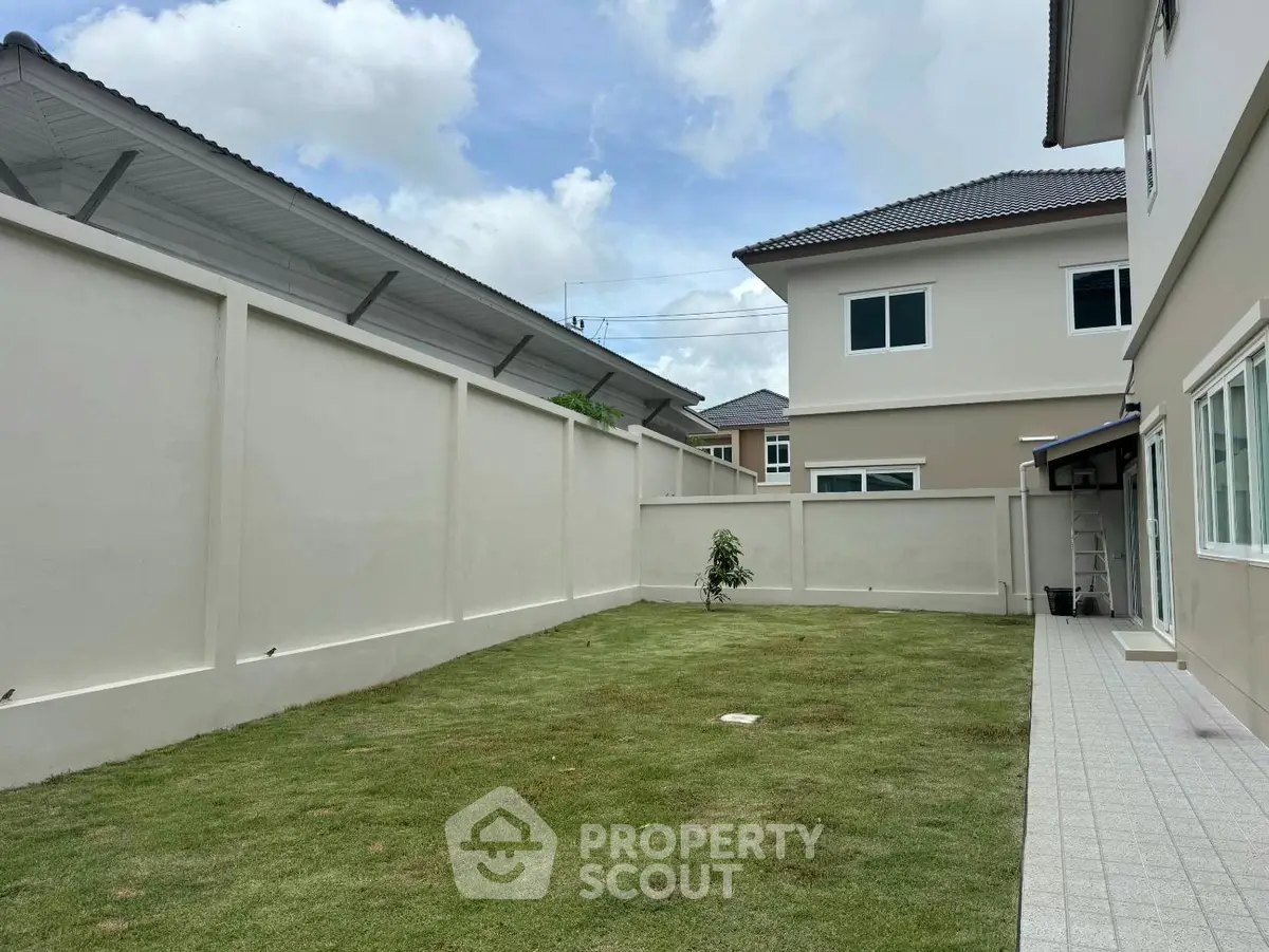 Spacious backyard with lush green lawn and modern house exterior, perfect for family gatherings.