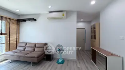 Modern living room with sleek sofa, air conditioning, and stylish decor in a bright apartment.