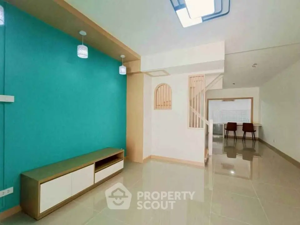 Spacious modern living room with vibrant teal accent wall and sleek tile flooring.
