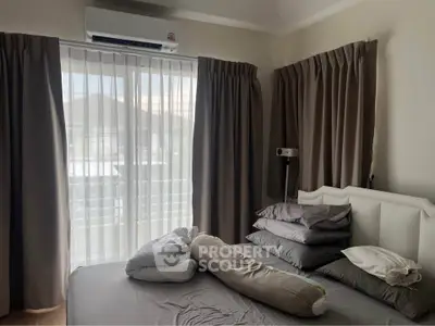 Cozy bedroom with natural light and air conditioning, featuring a neatly made bed and elegant curtains.