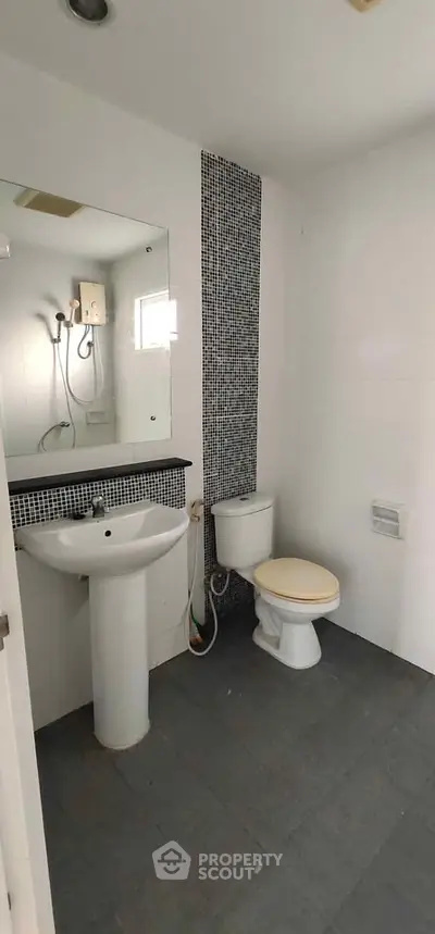 Modern bathroom with sleek design, featuring a pedestal sink and wall-mounted shower.