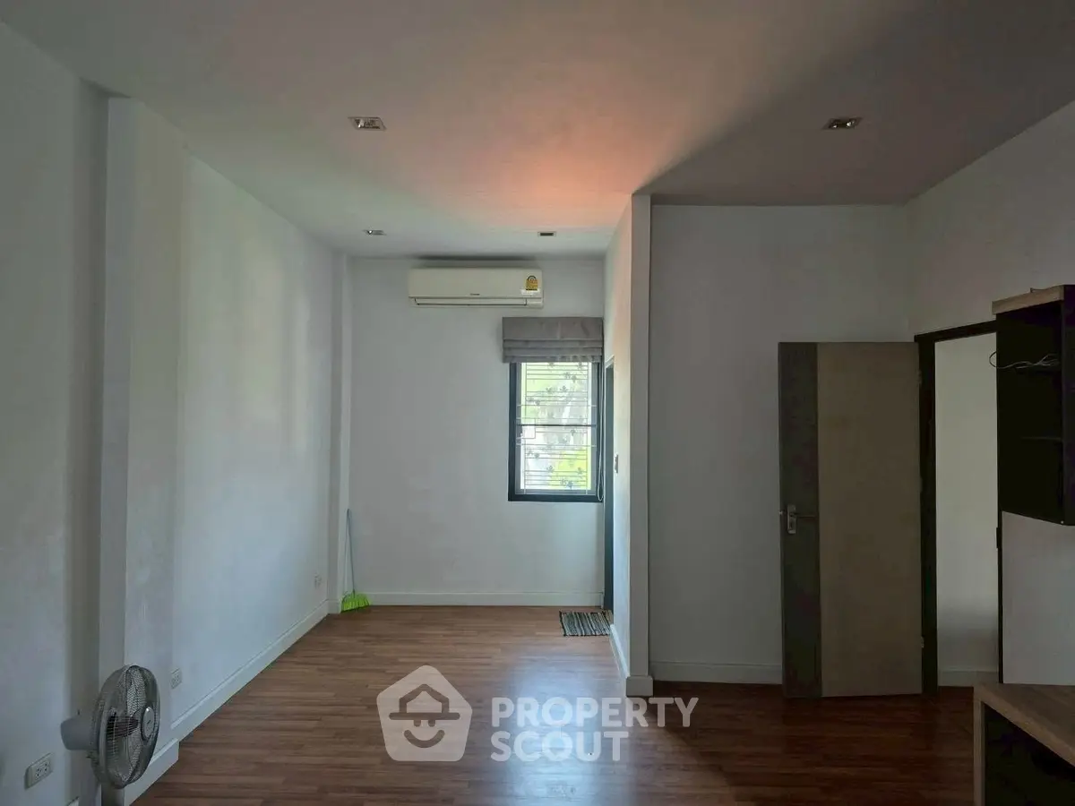 Spacious room with wooden flooring and air conditioning, ideal for customization.