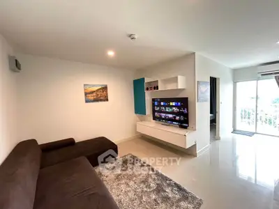Modern living room with sleek furniture and wall-mounted TV in a bright apartment.