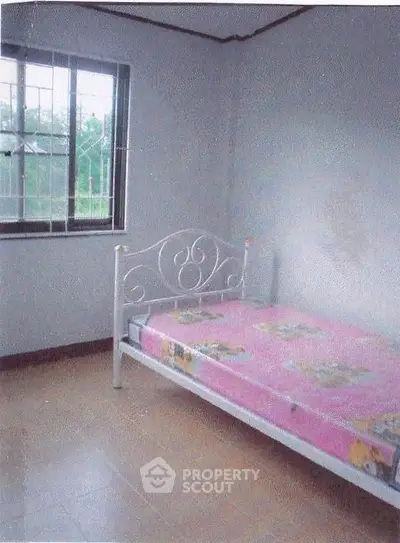 Cozy bedroom with natural light and simple decor, featuring a single bed and tiled flooring.