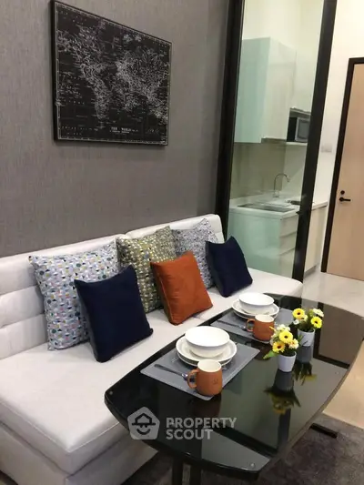 Stylish modern living room with cozy sofa, decorative pillows, and elegant dining setup in a compact space.