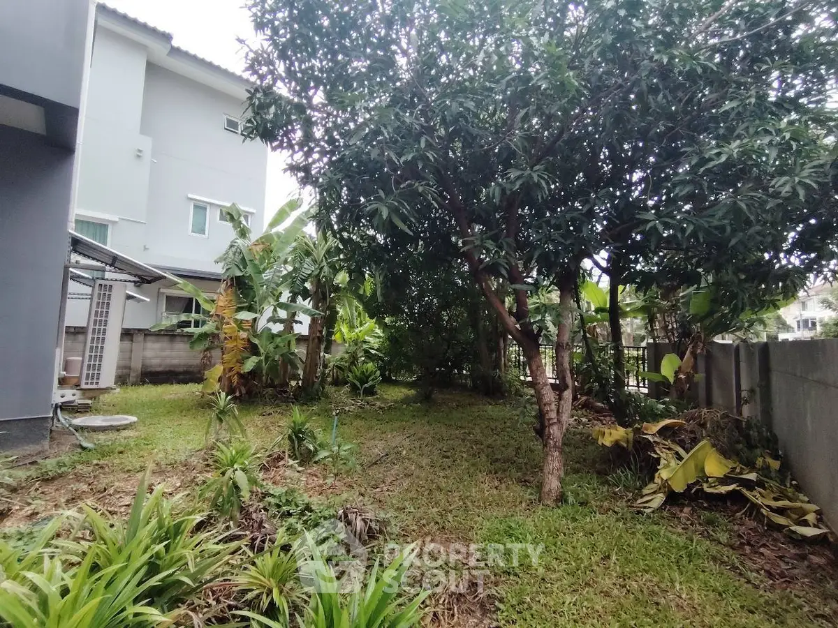 Spacious garden area with lush greenery and mature trees in a residential property.