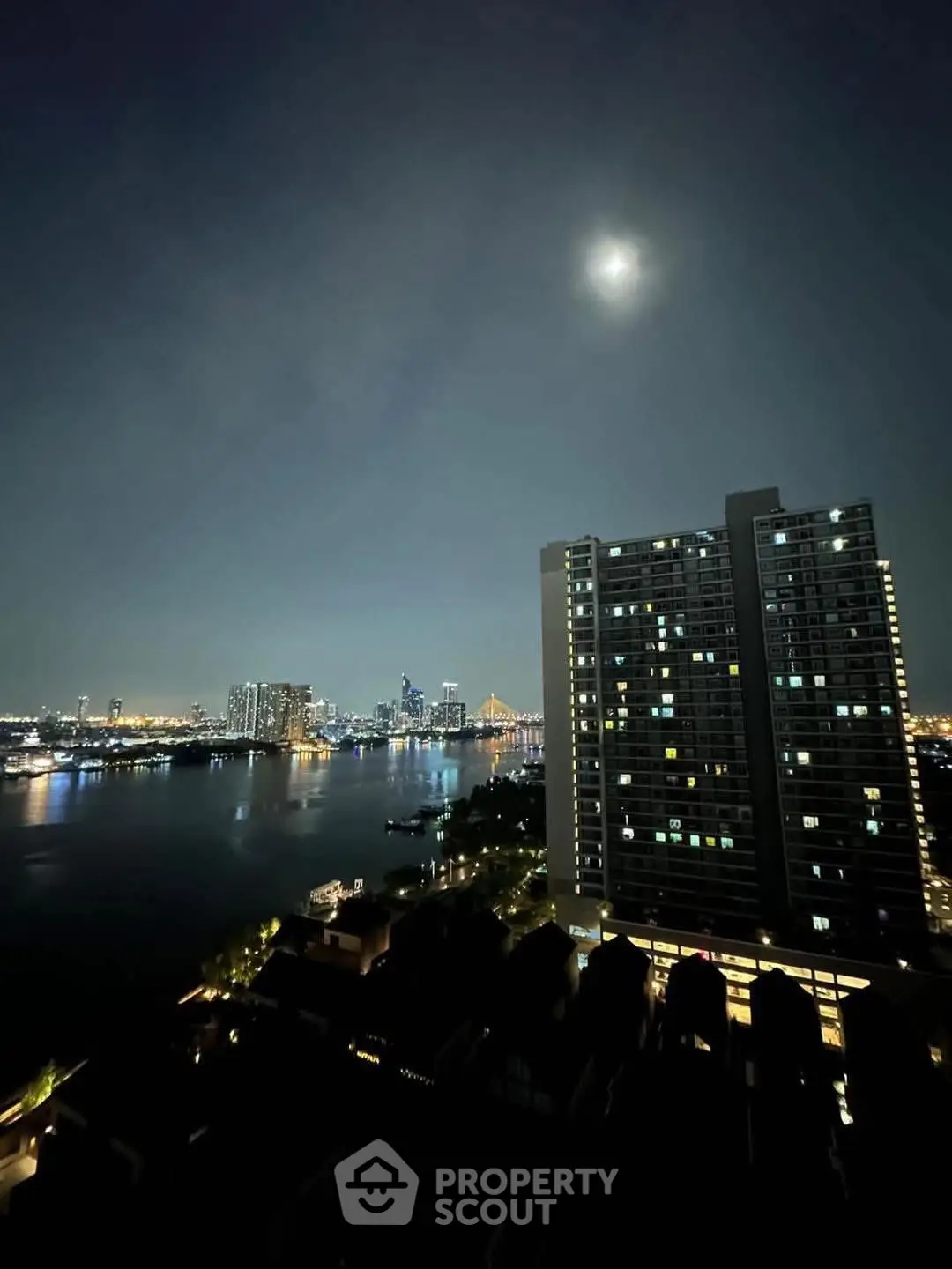 Stunning night view of city skyline and river from high-rise balcony, perfect for urban living.