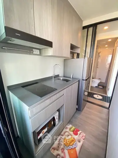 Modern compact kitchen with sleek cabinetry and integrated appliances in a stylish apartment.