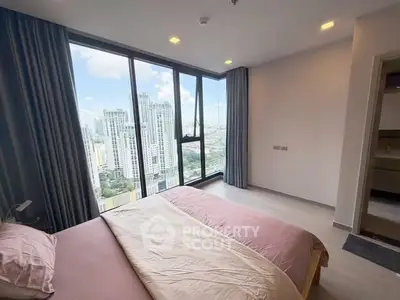Modern bedroom with stunning city view from floor-to-ceiling windows in high-rise apartment.