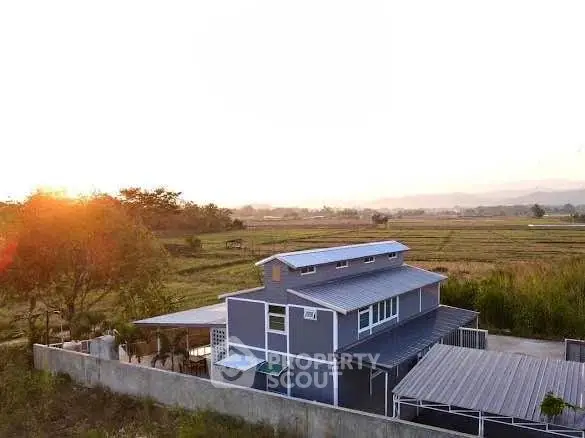 Modern two-story house with scenic countryside view at sunset.