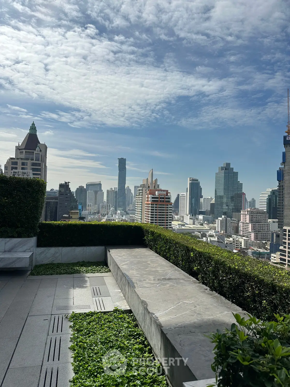 Stunning rooftop view of city skyline with lush greenery and modern architecture.