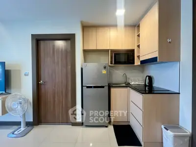 Modern compact kitchen with sleek appliances and wooden cabinetry in a cozy apartment setting.