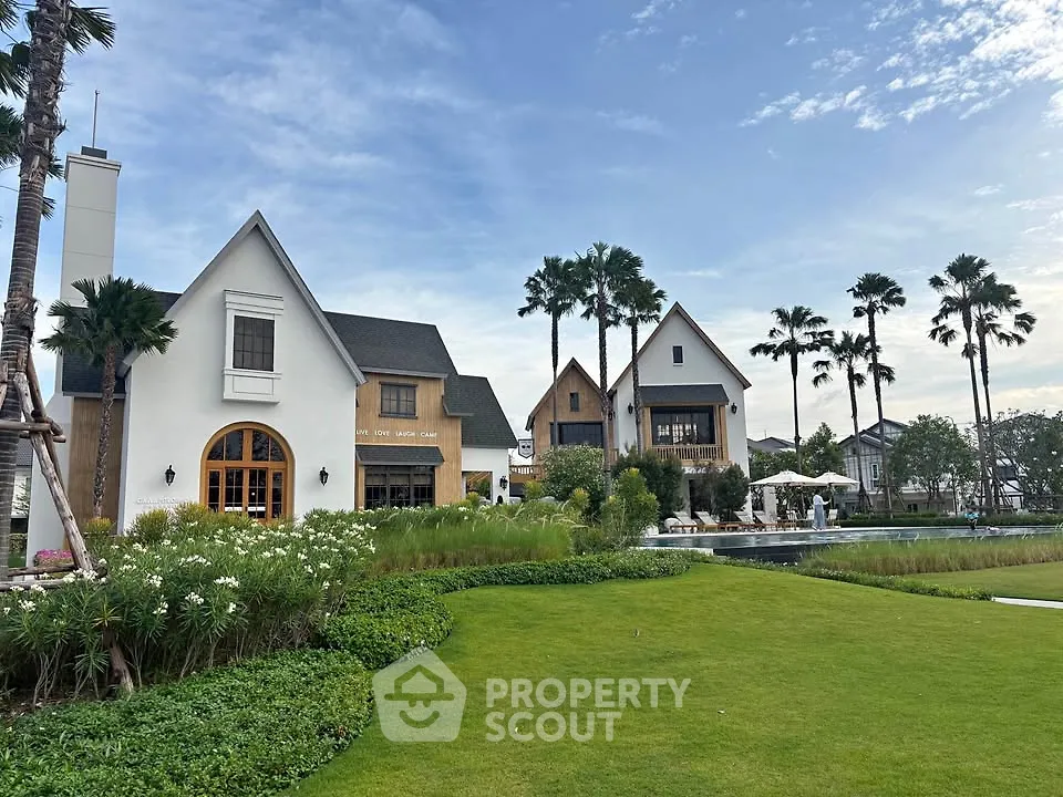 Charming modern houses with lush garden and palm trees under a clear blue sky.