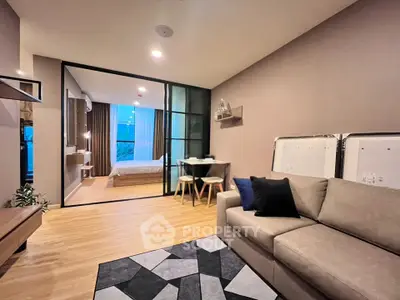 Modern open-plan living room with cozy sofa and stylish decor leading to a bright bedroom.