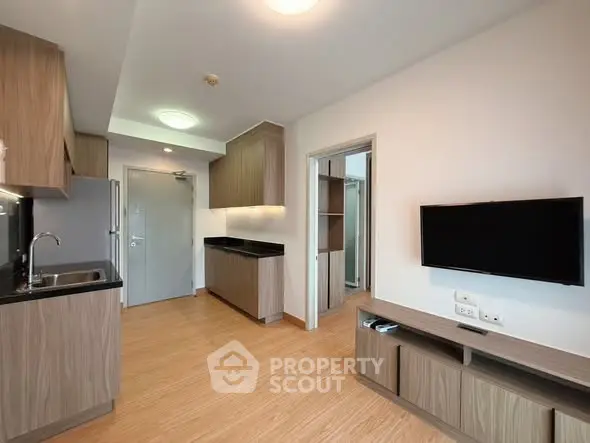 Modern open-plan living room with sleek kitchen and wall-mounted TV