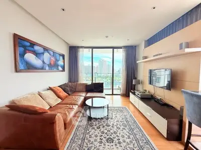 Spacious living room with modern decor and city view, featuring a cozy leather sofa and entertainment center.