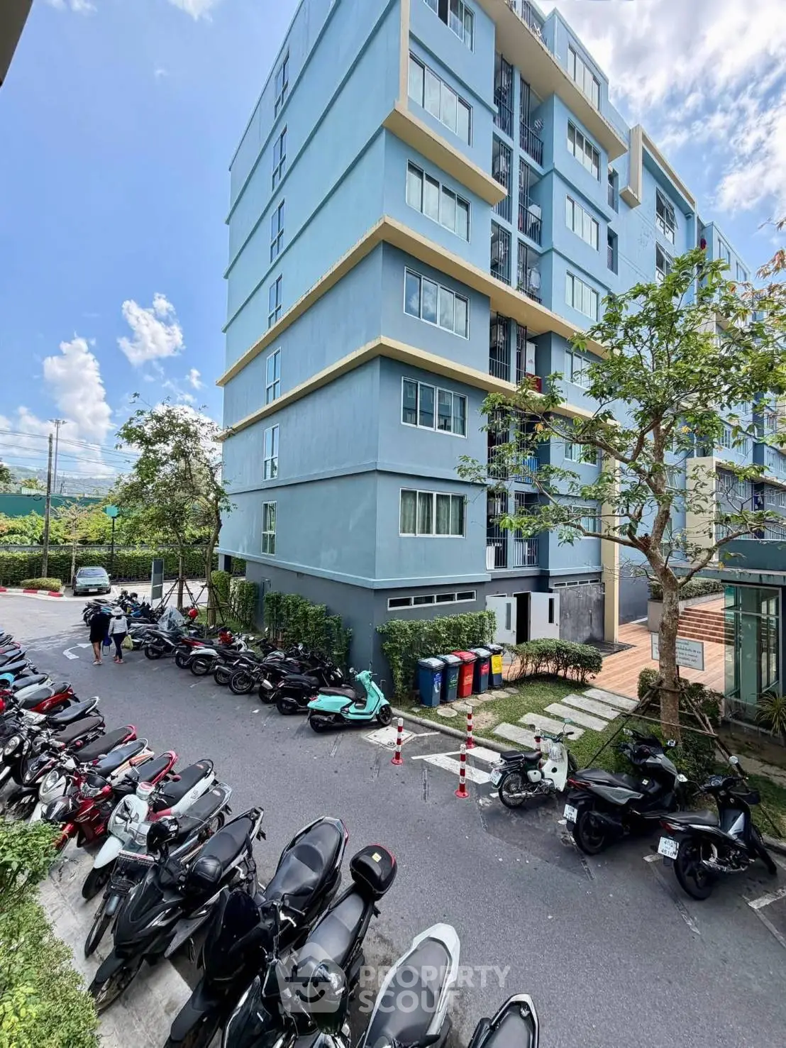 Modern apartment building with street view and parked motorcycles, showcasing urban living convenience.