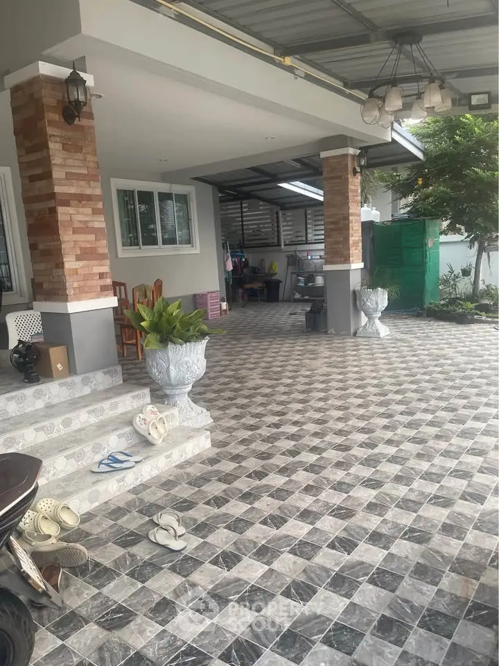 Spacious covered patio with stylish tiled flooring and brick columns, perfect for outdoor relaxation.