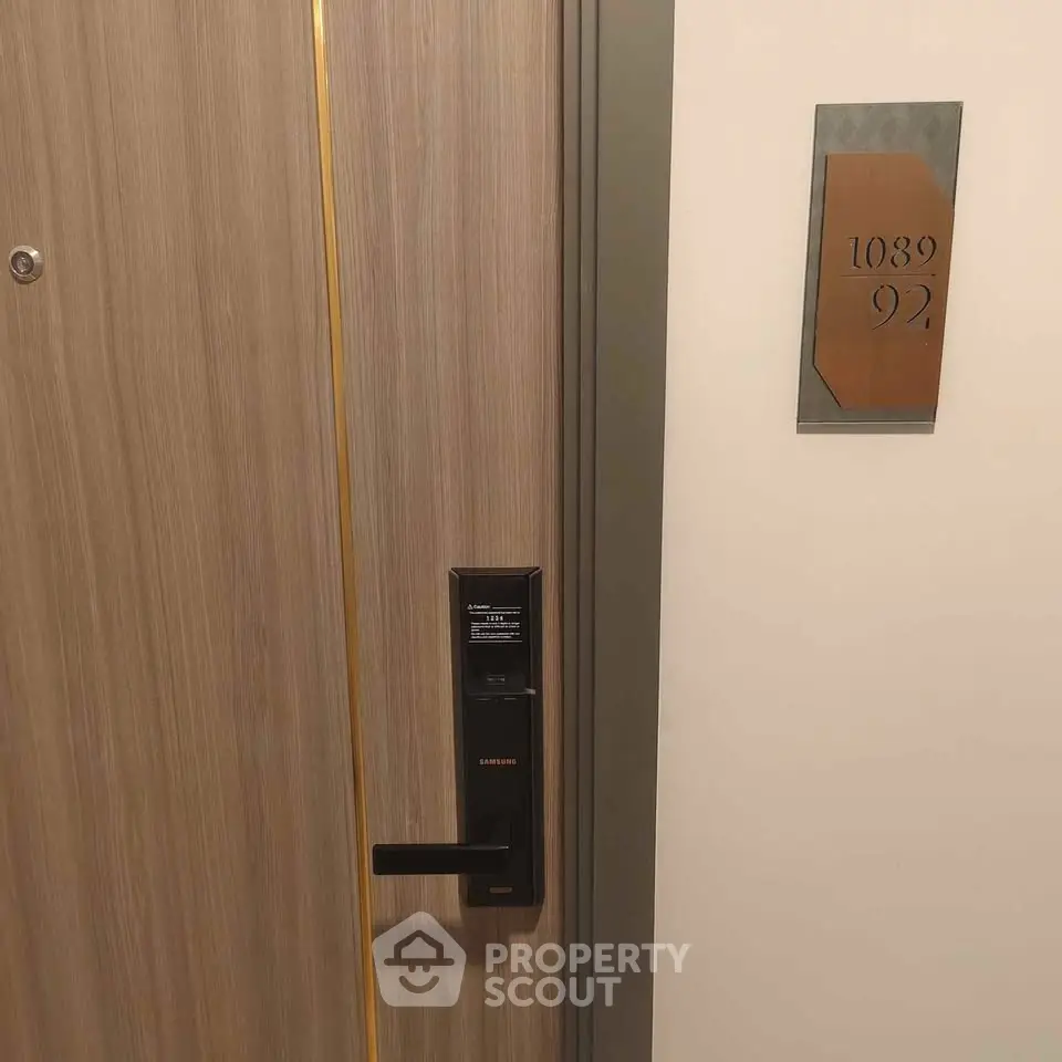 Modern apartment door with electronic lock and room number plaque, showcasing secure entry features.