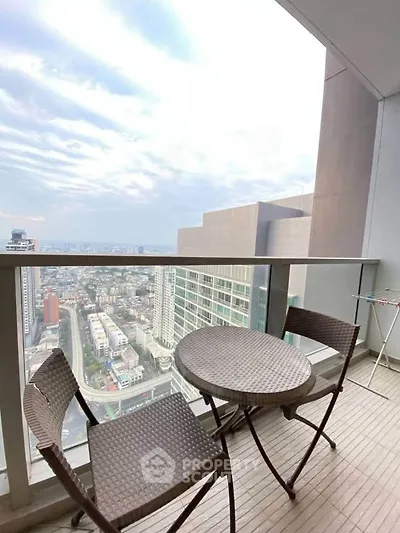 Stunning high-rise balcony with panoramic city views and cozy seating area.