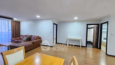 Spacious living room with wooden flooring and modern furniture in a cozy apartment.