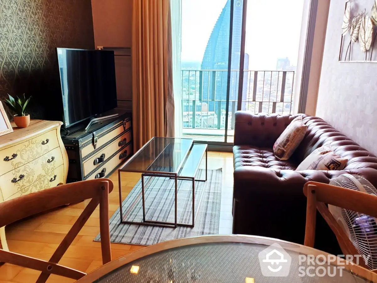 Elegant living room with classic leather sofa and glass coffee table, complemented by a charming city view from the balcony, ideal for urban living.