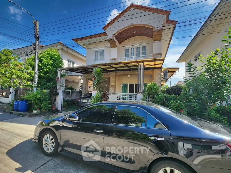 Charming two-story house with lush garden and carport in a serene neighborhood.