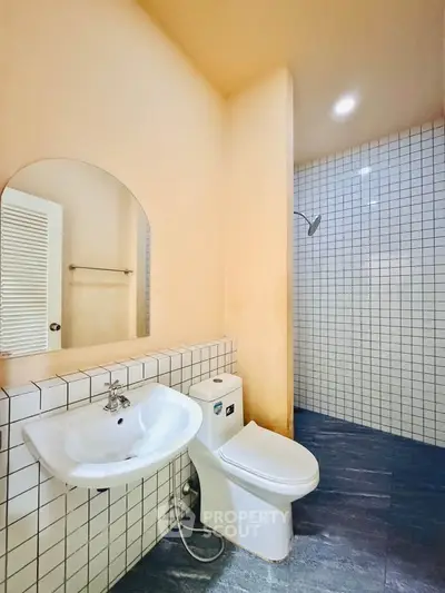 Modern bathroom with sleek design featuring a white sink, toilet, and tiled shower area.
