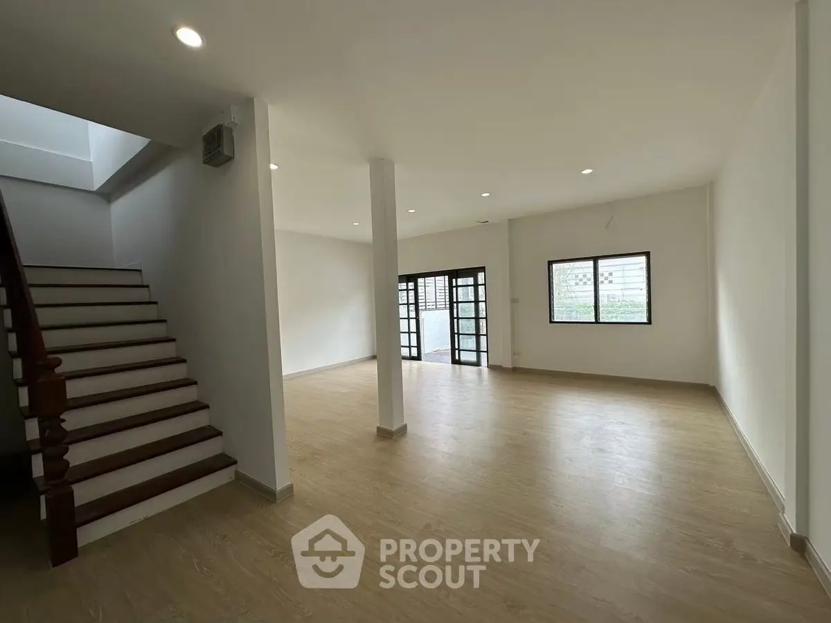 Spacious open-plan living area with wooden flooring and natural light