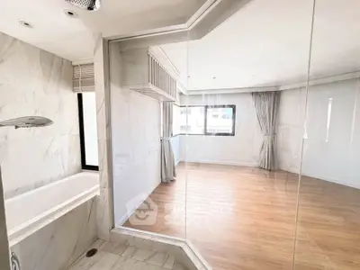 Spacious modern bathroom with glass partition and wooden flooring