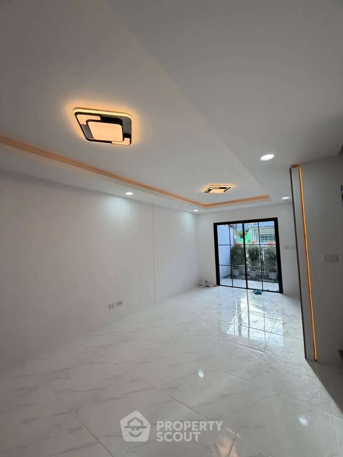Modern living room with sleek lighting and large glass doors leading to a garden view.