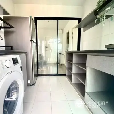 Sleek modern laundry room with high-end washing machine, ample storage, and elegant glass door leading to a bright interior space.