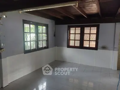 Spacious room with tiled floor and large windows in a rustic setting