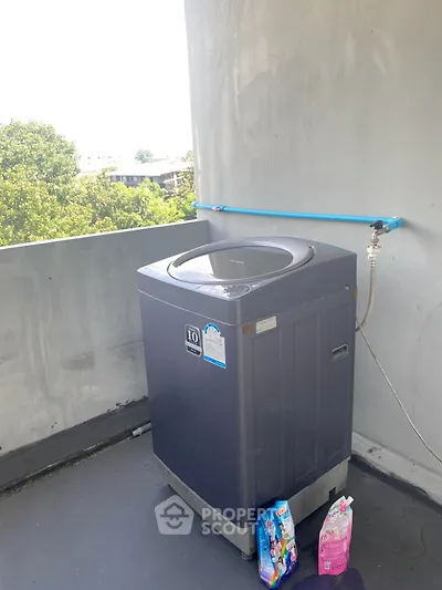 Outdoor washing machine setup on balcony with city view