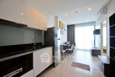 Modern open-plan living room with sleek kitchen and dining area, featuring natural light and contemporary design.
