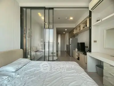 Modern studio apartment with glass partition, sleek furniture, and natural light.