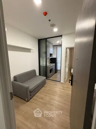 Modern compact living room with sleek kitchen and cozy sofa, perfect for urban living.